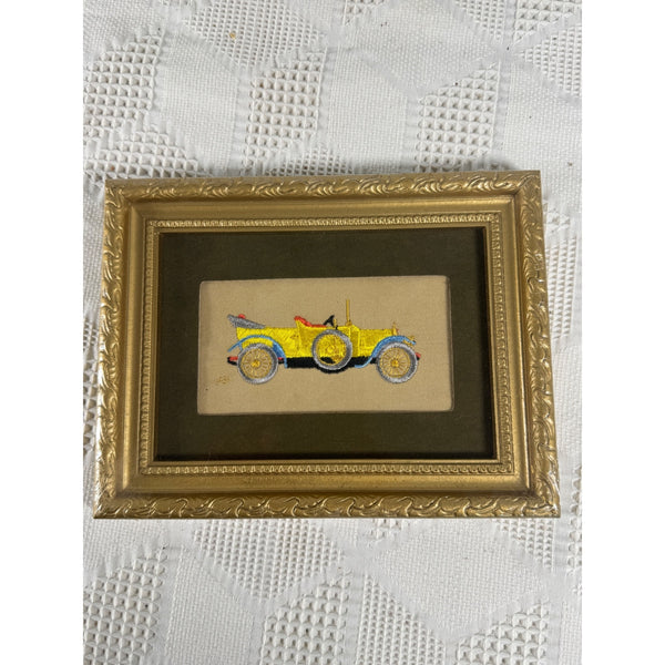Hand Embroidered Vintage Car Art 1914 Stutz Bearcat Needle Painters Guild 1969. A small framed vintage-style illustration of a yellow open-top car, mounted in an ornate gold frame and placed on a white textured fabric background.