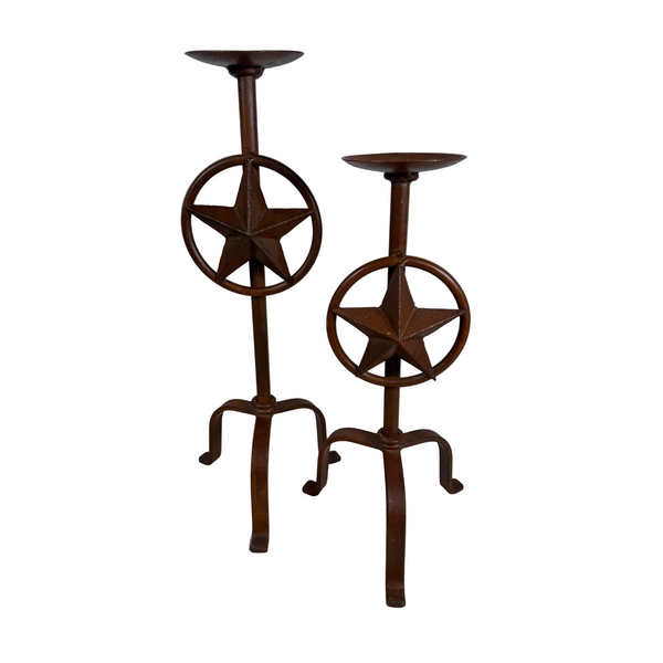 Rustic Iron Texas Star Candle Holders Set Of 2 Western Style Decor Rust Finish. Two rustic dark brown metal candlestick holders with star and circle designs, standing on a textured light surface against a plain gray wall.