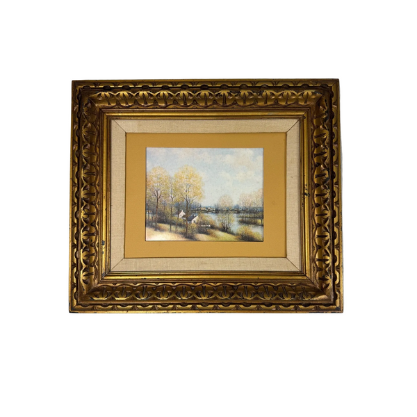 Vintage Landscape Art Print By Jean-Louis Vergne In Ornate Gold Frame No Glass. A framed landscape painting featuring a winter river scene with bare trees and a small cottage, surrounded by a wide gold-toned mat and an ornate carved gold frame, displayed against a light gray wall.