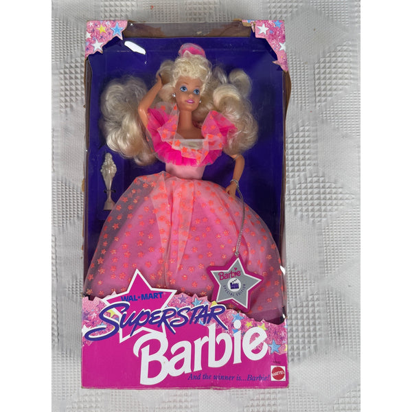 A vintage Mattel Barbie Superstar doll in its original window box packaging, featuring a blonde doll in a pink dress with gold stars, set against a textured gray background.