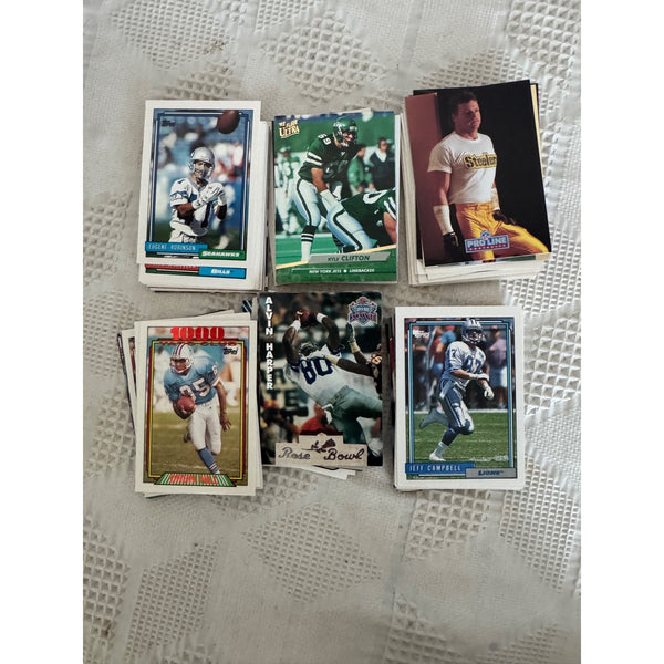 Lot Of 1990s Football Trading Cards Featuring Mixed Group NFL Teams and Players . Six stacks of vintage football trading cards arranged on a white textured lace cloth background.