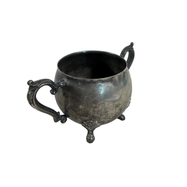 Leonard Silver Plated Vintage Sugar Bowl With Ornate Handles and Footed Design. An antique silver-toned metal pitcher with ornate handles and a footed base, resting on a white textured lace cloth.