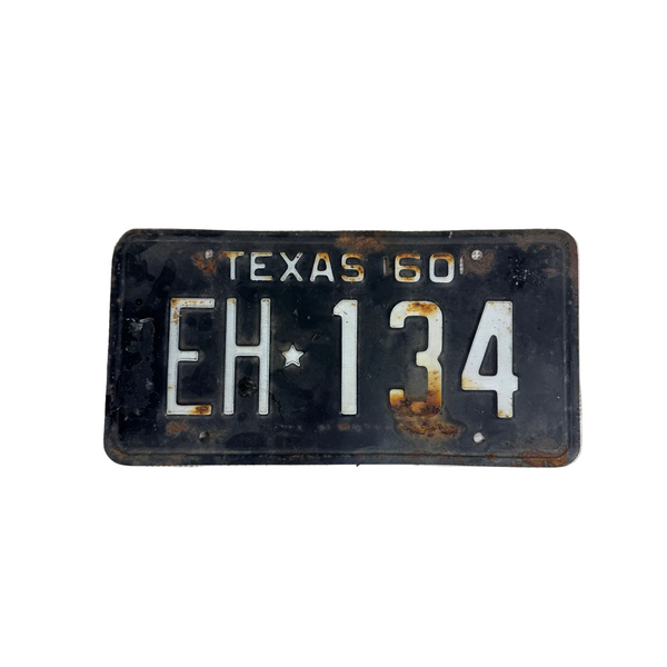 Vintage 1960 Texas License Plate Black w White Embossed Lettering EH 134 Rustic. A vintage 1960 Texas license plate with the registration EH 134, featuring a black background with white lettering and visible rust and wear, displayed on a textured white surface.