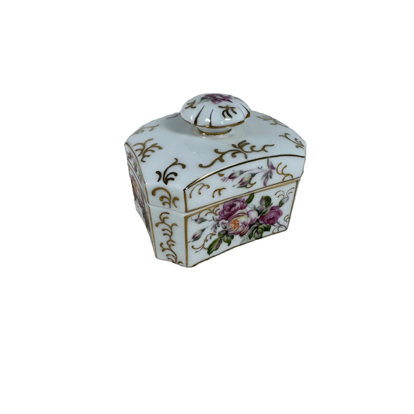 Vintage Matson Hand Painted Porcelain Trinket Box w Floral and Gold Design Japan. A small white porcelain lidded box decorated with gold floral scrollwork and pink and purple flowers, placed on a textured cream lace cloth.