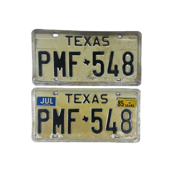 Vintage 1975 Texas License Plates PMF 548 Pair White w Black Embossed Lettering. Two vintage Texas license plates with the plate number PMF 548, one dated July 1985 and one more recent, displayed on a white textured fabric background.