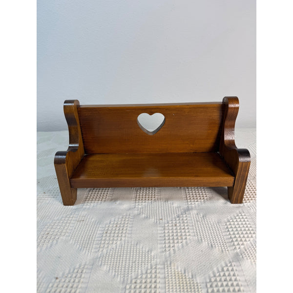 Handcrafted Wooden Doll Bench Heart Cutout Design Wall Mount Or Freestanding . A miniature wooden bench with a heart-shaped cutout in the center of the backrest, shown on a textured white surface against a light gray wall.