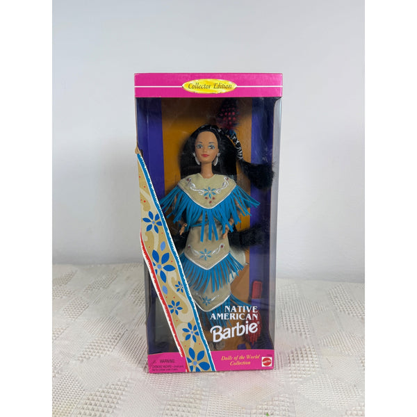 Native American Barbie doll in its original retail packaging, featuring a turquoise and beige fringed outfit with a black wig, set against a plain light gray background. Native American Barbie Dolls Of The World Collection 1996 Special Ed 15304 NIB 