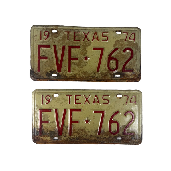 Vintage 1974 Texas License Plates Pair FVF 762 White w Red Embossed Lettering. Two vintage 1974 Texas license plates with the plate number FVF 762, displayed vertically on a textured white fabric background.