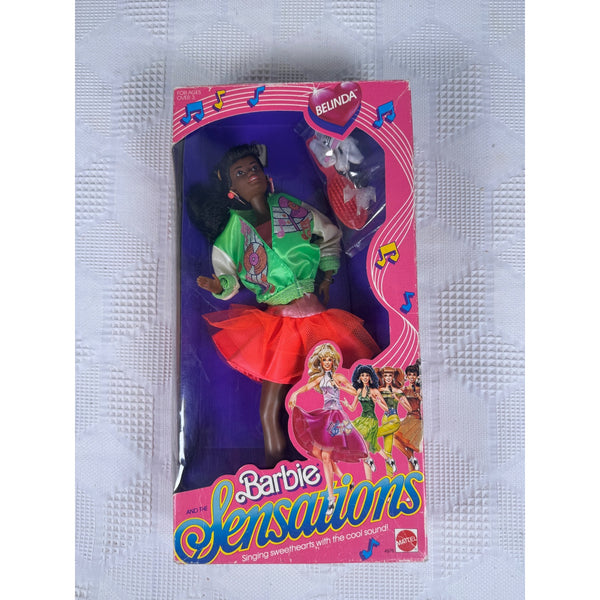 A vintage Barbie Sensations doll in its original pink and purple packaging, featuring the character Bumblebee in a green and white top with a red skirt, set against a textured white background.