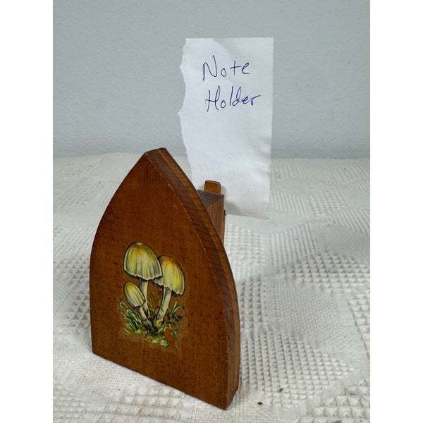 A wooden note holder with a mushroom illustration, holding a piece of paper that says 'Note Holder'.