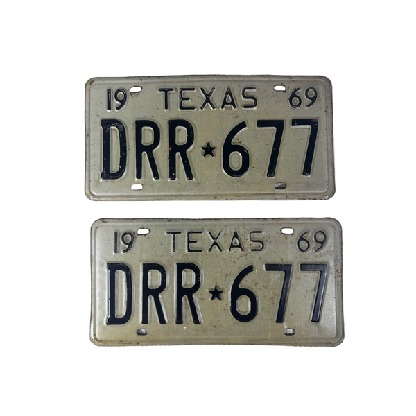 Vintage 1969 Texas License Plate Pair DRR 677 White w Embossed Black Lettering. Two vintage 1969 Texas license plates with the plate number DRR 677, displayed on a textured white fabric background.