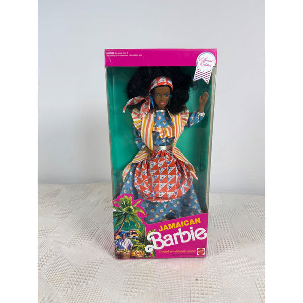 A vintage 1985 Jamaican Barbie doll in its original window box packaging, featuring a doll with black hair wearing a colorful patterned dress and headscarf, set against a green background with a pink and yellow Jamaican-themed base. Jamaican Barbie Dolls Of The World Collection 1991 Special Edition 4647 NIB 