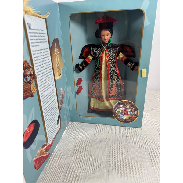 A collectible Chinese doll dressed in an ornate black, red, and gold traditional robe, displayed inside its light blue open packaging box with printed inserts. The Great Eras Chinese Empress Barbie 1996 Collector Edition Doll 16708 NIB