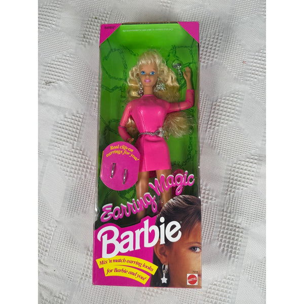 Vintage Barbie Earning Magic doll in its original pink and green packaging, placed on a textured white fabric background.