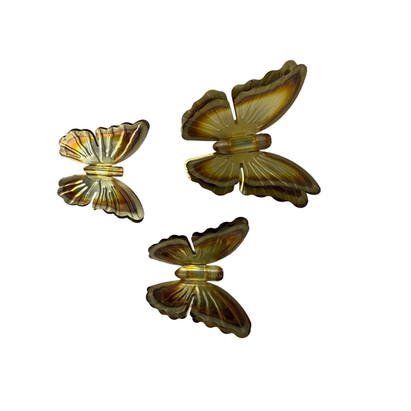 Vintage Brass Butterfly Wall Hangings Set of 3 Gradient Tones Double Wing Design. Three vintage iridescent butterfly-shaped brooches in a gold and amber tone, displayed on a textured white fabric background.