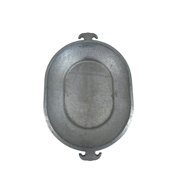 Guardian Service Aluminum Oval Serving Tray With Textured Design Handle Vintage. An oval-shaped gray cast iron skillet with two small handles on the rim, photographed from directly above on a textured off-white surface.