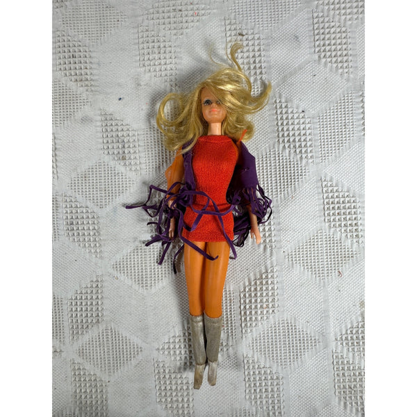Vintage 1971 Live Action PJ Doll Friend of Barbie TNT Bendable Legs Fringe Lashes. Vintage fashion doll with blonde hair, wearing a red top, orange pants, and a purple fringed jacket, lying on a textured white surface.