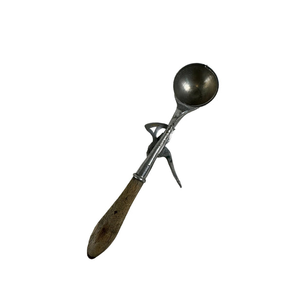 Antique Gem Soda Fountain Ice Cream Scoop 1895 Dipper Metal w Wooden Handle. A vintage metal ice cream scoop with a wooden handle, resting on a textured white paper towel.