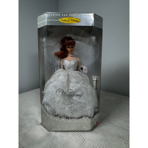 A collectible Barbie doll in a white wedding gown, still inside its original packaging box. The box features a clear plastic front window, a silver-gray base, and a yellow 'Collectible Edition' label on the top.