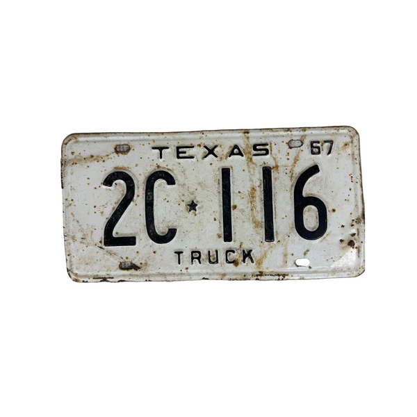 Vintage 1967 Texas Truck License Plate 2C 116 White w Black Embossed Lettering. A vintage distressed Texas license plate reading '2C 116 TRUCK' with 'TEXAS 67' at the top, photographed against a textured off-white fabric background.