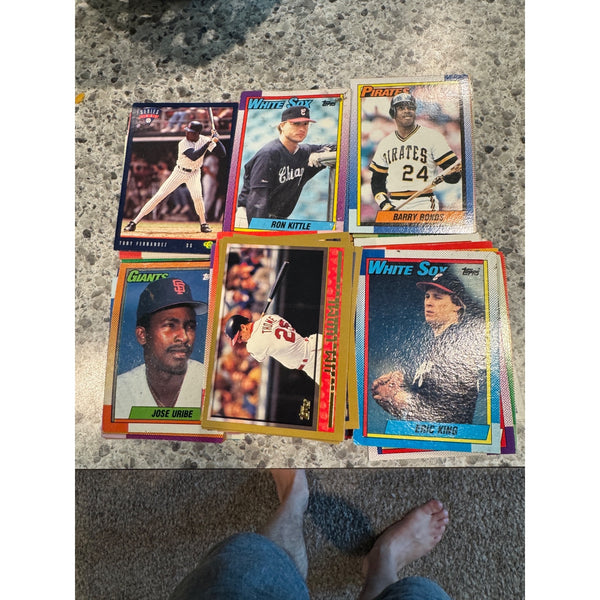 A set of sixBulk 3lb Lot Baseball Trading Cards 1990 and Newer Mixed Teams Players Makers.  vintage 1980 Topps baseball trading cards arranged on a speckled granite countertop, with a person's bare feet visible at the bottom of the frame.