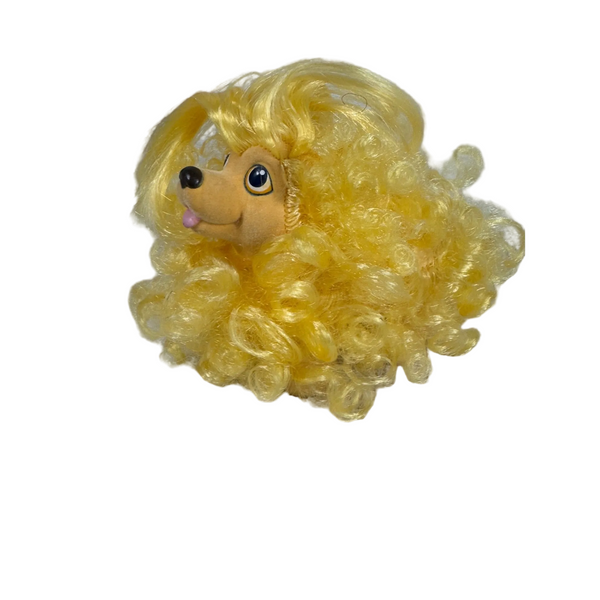Vintage Hasbro Sweetie Pup Yellow Cocker Spaniel 1989 Collectible Retro Toy. A small plush dog toy with bright curly yellow hair, a tan face, and large black eyes, resting on a white textured fabric surface against a light gray wall.