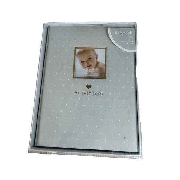 Little Blossoms Baby Memory Book by Pearhead Gray Polka Dot Keepsake NIB. A silver baby photo album with a light gray cover patterned with tiny white dots, featuring a sample baby photo in the center and the text 'MY BABY BOOK' below it. The album is sealed in a clear plastic protective sleeve and photographed on a textured beige fabric background.