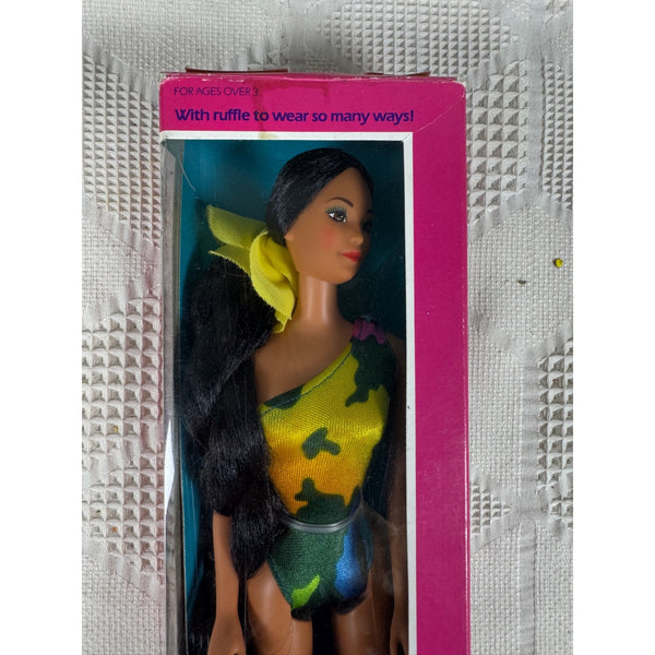 A vintage Barbie doll in a yellow and green camouflage swimsuit, still in its original pink packaging, displayed on a textured white surface. Tropical Miko Barbie Doll Vintagem1985 Mattel w One Piece Bathing Suit 2056 NIB