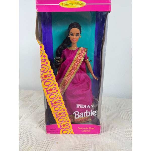 A boxed Barbie doll from the Collector's Edition series, featuring an Indian-themed doll wearing a pink sari with gold patterns. The product is shown inside its original retail packaging, standing on a white textured surface against a plain white background. Indian Barbie Doll Vintage 1995 Dolls Of The World Collection 14451 NIB