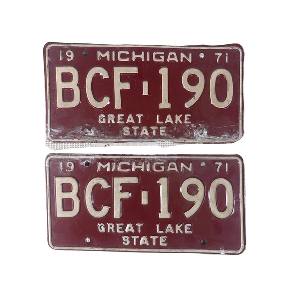 1971 Michigan State License Plates Pair BCF 190 Vintage Red w Embossed White. Two vintage 1971 Michigan license plates reading BCF-190, with a dark red background and cream lettering, displayed on a textured white surface.