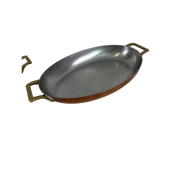 Paul Revere Limited Edition Oval Copper Au Gratin Pan With Brass Handles c1967. An oval metal pan with a brushed silver interior and a copper-brown exterior, featuring two brass-colored handles, resting on a textured white tablecloth.