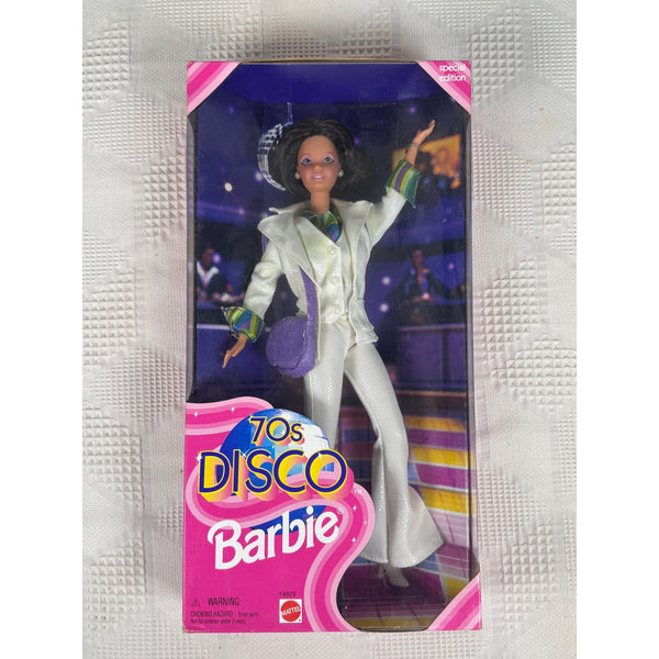 70s Disco Barbie Doll Special Edition 1998 Mattel Retro Collectible 19929 NIB. A 70s Disco Barbie doll in its original window box packaging, featuring Barbie in a white 70s style jacket and skirt with purple and green accents, set against a textured white background.