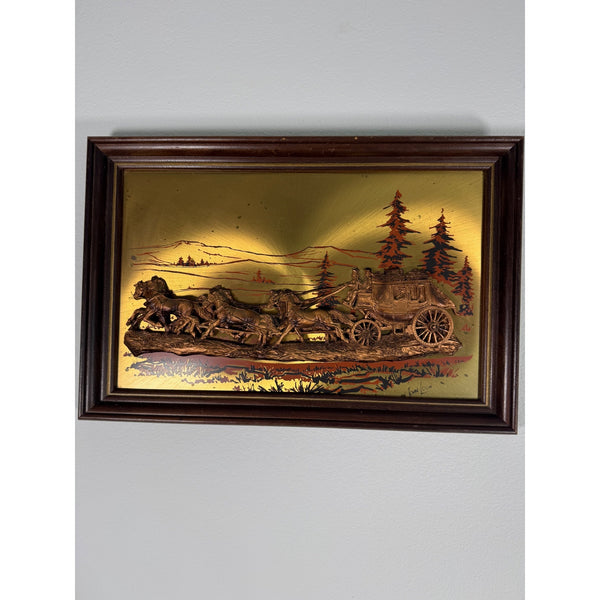 John Louw Stagecoach Embossed Copper Art In Wood Frame Western Americana 1970s. A framed vintage-style relief sculpture depicting a horse-drawn carriage scene with trees and mountains, mounted on a light gray wall.