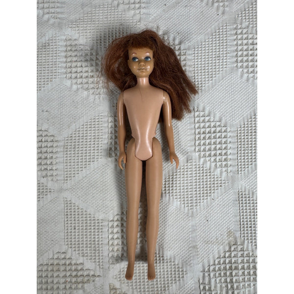 Vintage 1960s Skipper Doll Little Sister Of Barbie w Titian Hair Blue Eyes Japan. A vintage plastic doll with long brown hair, a tan skin tone, and blue eyes, lying on a textured white quilted blanket.