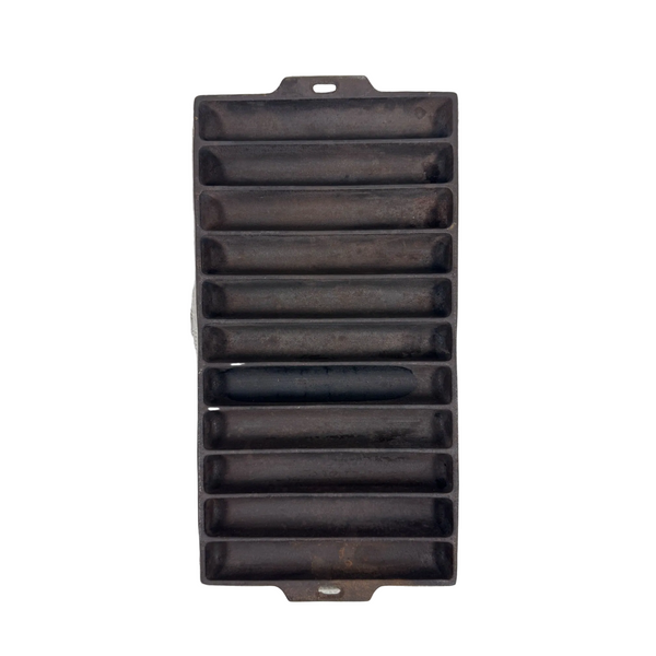 Wagner Ware Cast Iron Breadstick Pan 22E Vintage 1930s Sidney Ohio Bakeware 1326. A rectangular dark cast iron mold with multiple parallel slots, photographed from above on a textured off-white fabric background.