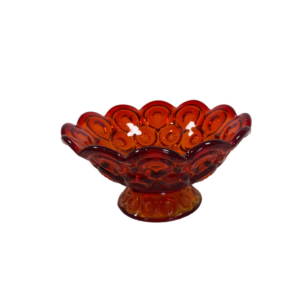 LE Smith Amberina Glass Compote Bowl Moon & Star Pattern Pedestal Base Vintage . An amber red glass pedestal bowl with a scalloped rim and embossed circular pattern, set on a textured white surface against a light gray background.