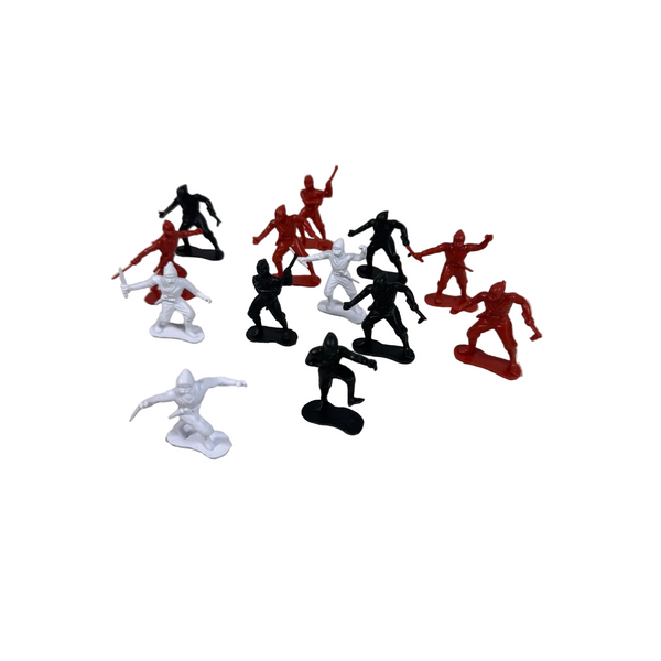 Vintage Plastic Ninja Figurines Set Of 13 In Red Black and White Army Men Style. A set of small plastic toy soldier figures in red, black, and white, arranged on a textured off-white surface against a light gray background.