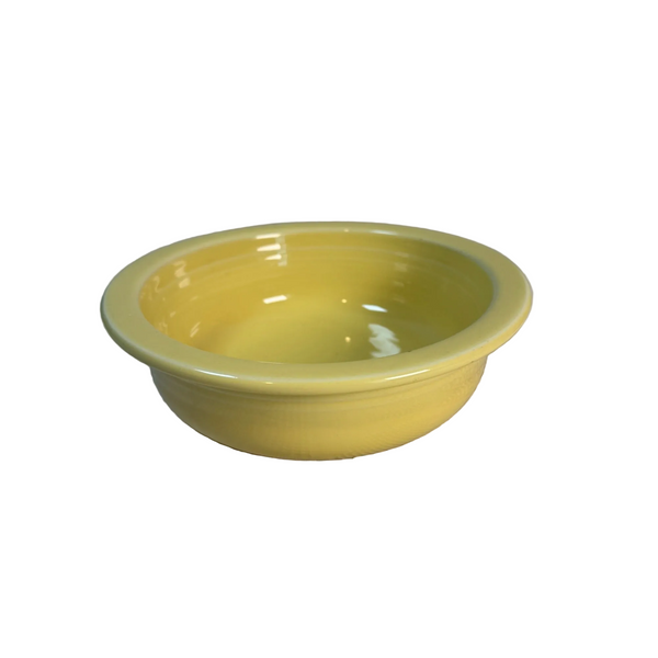 Fiesta Yellow Ceramic Vegetable Serving Bowl by Homer Laughlin China Co USA . A yellow ceramic bowl with a glossy finish, resting on a textured white tablecloth against a neutral gray background.