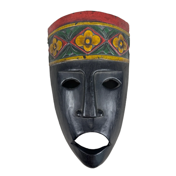 Hand Carved Wooden Mask Temor Indonesia Wall Hanging Black with Floral Accents . A hand-painted wooden African-style mask with a dark charcoal face, featuring a red, yellow, and green patterned headband, displayed against a textured white background.
