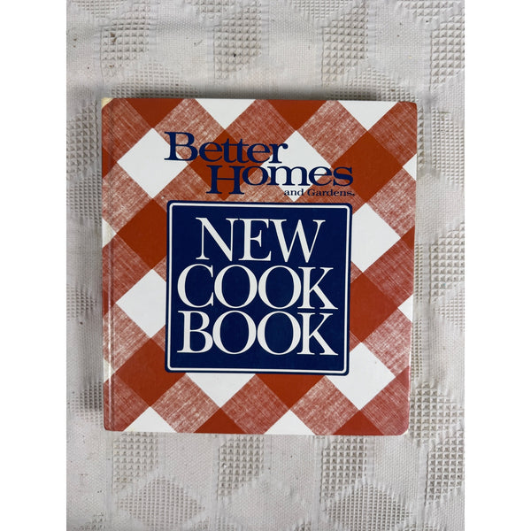 Better Homes and Gardens New Cook Book Hardcover Vintage 1989 Edition. A vintage 'Better Homes and Gardens New Cook Book' with a red and white gingham patterned cover, resting on a textured white fabric background.