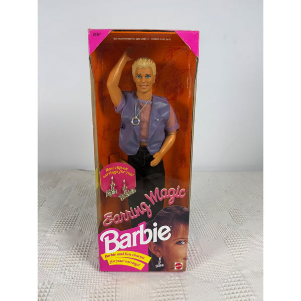 A boxed Barbie doll standing upright in its original retail packaging. The package shows a blonde Barbie figure wearing a lavender shirt and black pants, with large pink and white Barbie branding and product text on the front. Earring Magic Ken Doll Vintage 1992 Mattel Includes Clip On Earrings 2290 NIB