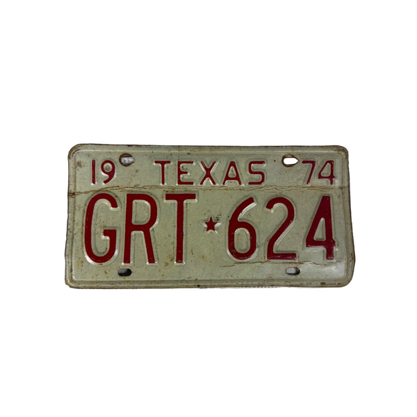 Vintage 1974 Texas License Plate GRT White w Red Embossed Lettering Rustic. A vintage 1974 Texas license plate reading GRT 624, featuring red lettering and numbers on a weathered off-white background, displayed on a textured white fabric surface.